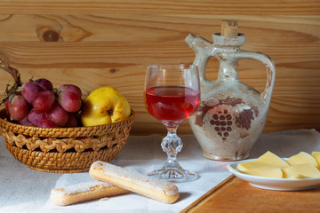 Obraz na płótnie Canvas jug glass of wine fruit and cheese on a platter on a wooden background