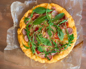 Home-made pizza with sausage, tomatoes and a cutaway, mushrooms and all-season arugula