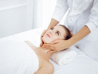 Obraz na płótnie Canvas Young and blonde woman enjoying facial massage in spa salon. Beauty concept