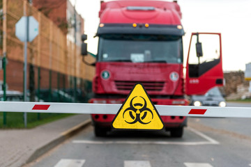 Truck standing at the barrier with a virus warning sign, Coronavirus containment concept