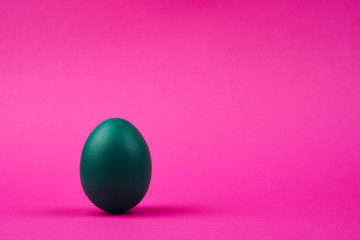 Colorful green easter egg on bright pink background