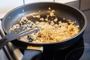 Chopped yellow onions frying in a pan.