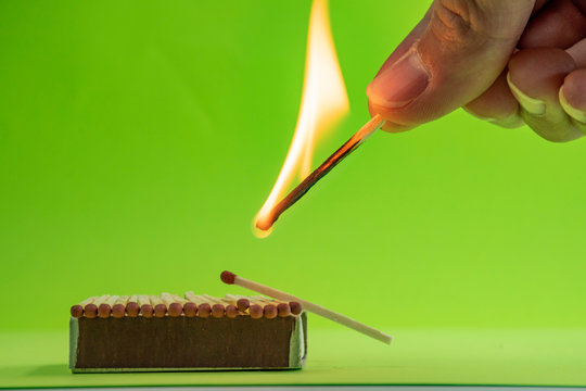 Burning match on a green background, matchbox.