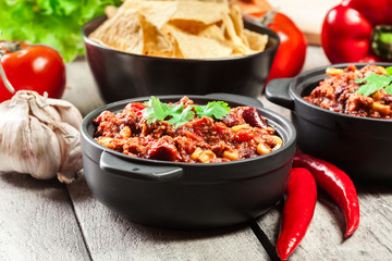 Bowls of hot chili con carne with ground beef, beans, tomatoes and corn - obrazy, fototapety, plakaty
