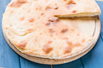 Pie with cheese, khachapuri on a blue wooden background.