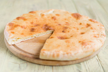 Pie with cheese, khachapuri on a wooden background.