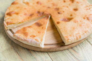 Pie with cheese, khachapuri on a wooden background.