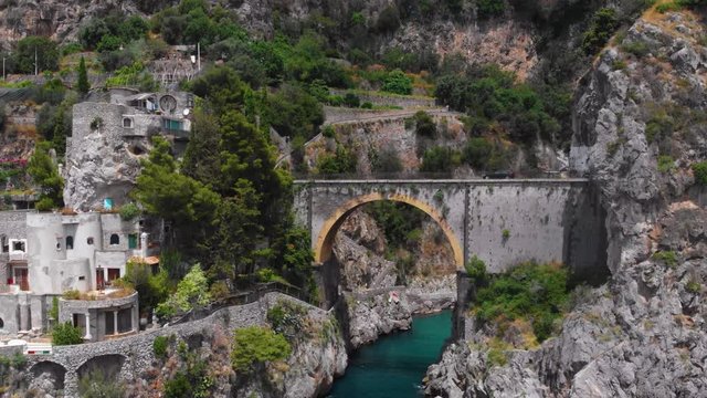 Aerial view inside bay of Fiordo di furore beach. Incredible beauty panorama of a mountains paradise. The rocky seashore of southern Italy. Sunny day. Stone bridge traffic, cars and motorcycle. Amalfi