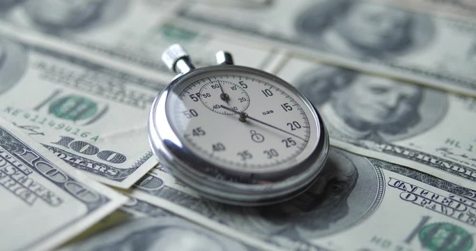 The stopwatch lies on the dollars. Time is money concept.