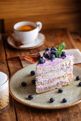 Fresh delicious piece of cake with blueberries, mint and coffee, side view, vertical