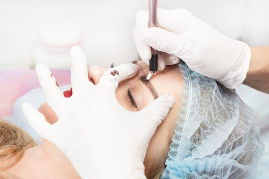 Microblading eyebrow tattoo procedure in a beauty salon for women.