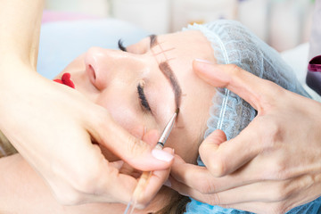 Microblading eyebrow tattoo procedure in a beauty salon for women.
