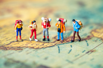 Miniature people: Group of backpacker on vintage world map using as business trip traveler adviser agency or explorer on earth background concept.