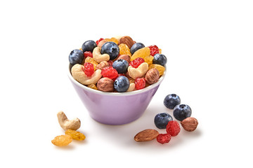 Nuts and dried fruit berries mix in bowl. Fitness diet super food. Energy cereal healthy meal. Muesli, blueberry, seeds, hazelnut, almond, oatmeal isolated on white, closeup.