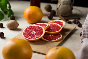 sliced grapefruit lies on a wooden Board surrounded by greenery, nuts and fabric