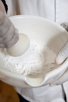 A chemist crushing tablets with a pestle and mortar.