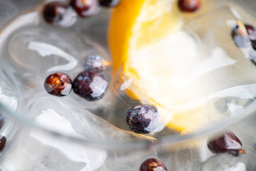Gin based cocktail with lemon slice and juniper berries in wine glass. Selective focus. Shallow depth of field.