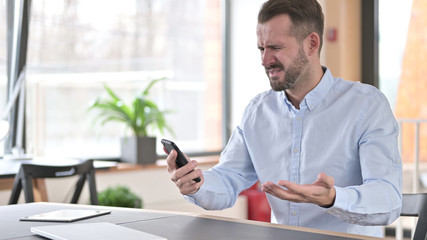 Young Man Reacting to Loss on Smartphone in Office