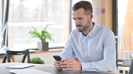 Fototapeta na wymiar Young Man Using Smartphone in Office