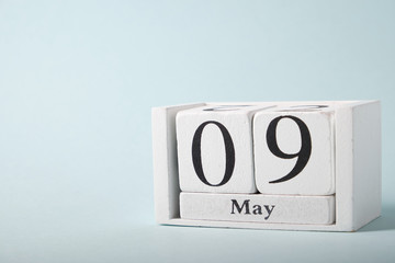 Wooden calendar on a blue background with the date of May 9