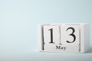 Wooden calendar on a blue background with the date of May 13