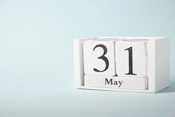 Wooden calendar on a blue background with the date of May 31