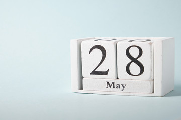 Wooden calendar on a blue background with the date of May 28