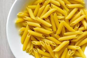 Yellow macaroni (pasta) in a white plate on the table
