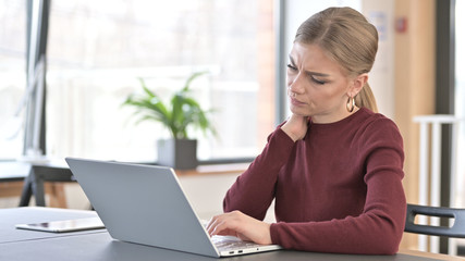 Young Woman with Neck Pain using Laptop in Office