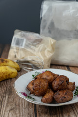 Popular Malaysian fritter snack deep fried banana balls or locally known as Cekodok Pisang in a plate over wooden background