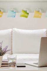 laptop with supplies on white wooden table in living room, vertical view.