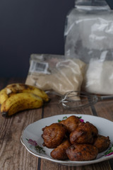 Popular Malaysian fritter snack deep fried banana balls or locally known as Cekodok Pisang in a plate over wooden background