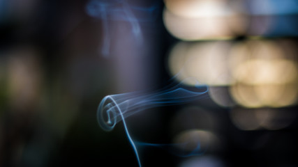 Artistic and relaxing isolated close up incense smoke movement indoors with beautiful bokeh background