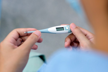 Closeup of man looking at thermometer, Male hand holding a digital thermometer when measures the temperature, People get fever, flu from virus check body temperature when stay at home - obrazy, fototapety, plakaty