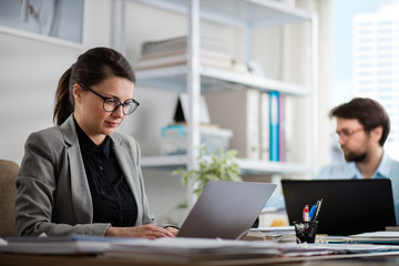 Colleagues on the job at the office. Young business woman and man busy working on a project.