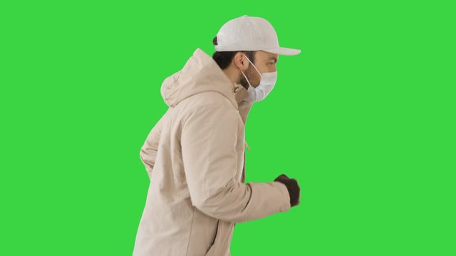 Ault man in jacket and in medical mask running on a Green Screen, Chroma Key.