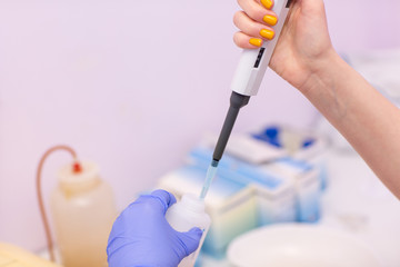 Laboratory assistant in medical laboratory holds test tube with blood and plasma and micrometer in his hand and do analysis.