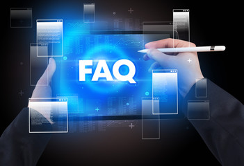 Close-up of a hand holding tablet with FAQ abbreviation, modern technology concept