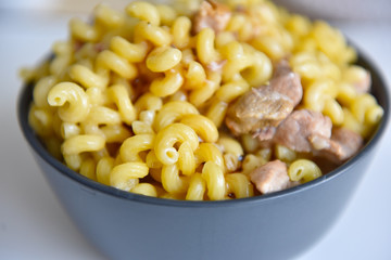 boiled macaroni with meat on a plate on a white background