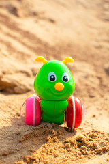 Bright green caterpillar toy in the sandbox. Funny children toy.