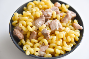 boiled macaroni with meat on a plate on a white background
