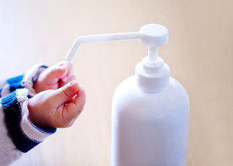 赤ちゃんの手と消毒用ボトルとコピースペース