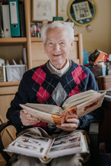 Old man looking at old albums with family photos