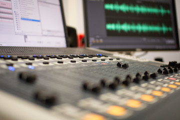 Professional audio mixing console with faders and adjustment knobs.