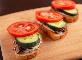 Slices of tomatoes and cucumbers on slices of wheat bread on a cutting Board close-up.