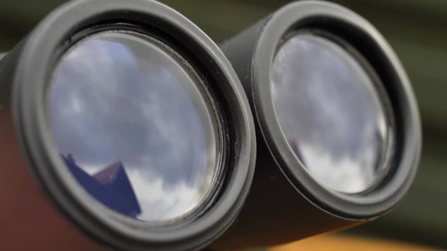Binoculars Front Lens Reflecting Light and Clouds Close Up