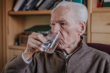 Fototapeta na wymiar Old man drinking water closeup