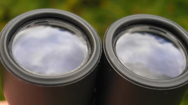 Binoculars Front Lens Reflecting Light and Clouds Close Up