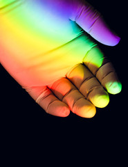 Gloved hand with rainbow light on black background
