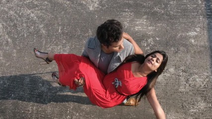 An young Indian Bengali brunette man in western wear taking his girlfriend moving in a slow circular motion on the rooftop. Indian lifestyle and holidays.